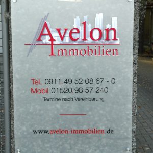 An Stein montiertes Plexiglasschild für Avelon Immobilien