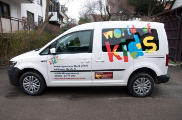Beklebter weißer VW Caddy mit dem bunten world of kids schriftzug