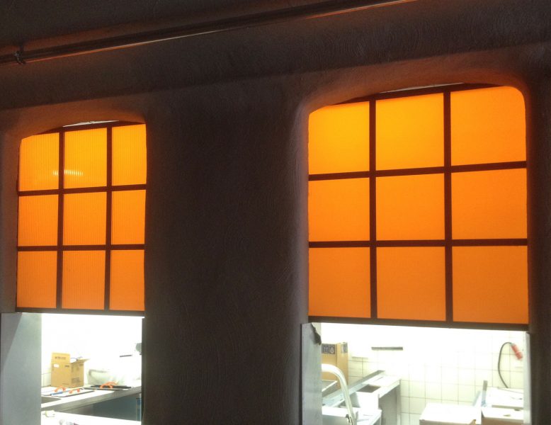 Plexiglasschilder mit orangfarbener Folie über einer Durchreiche