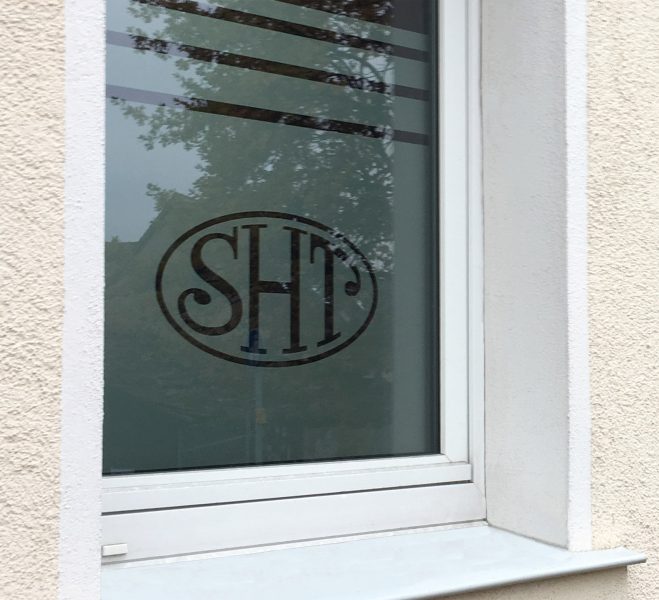 Außenansicht eines Fensters mit Glasdekorfolie und negativ herausgeschnittenem Logo