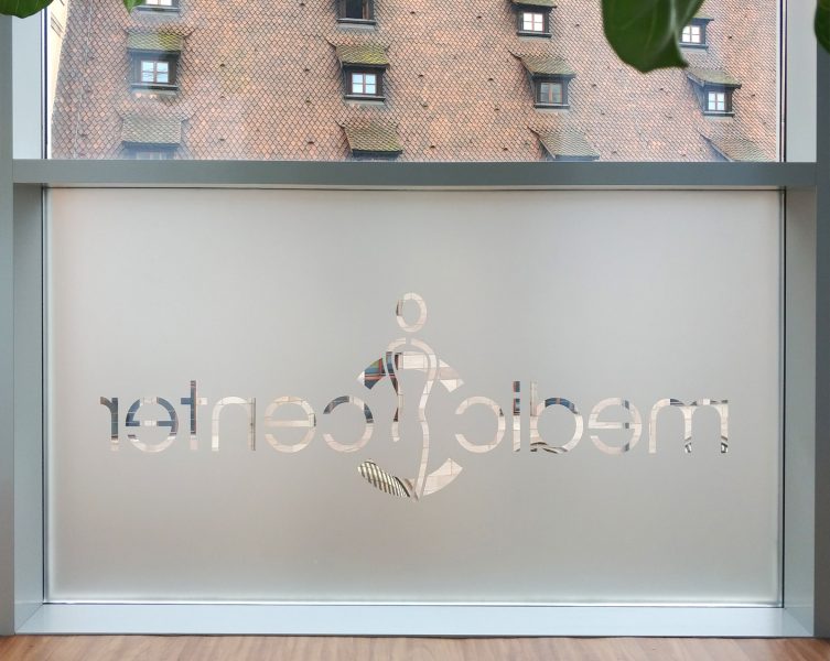 Folierung eines Fensters aus Glasdekor mit negativ herausgeschnittenem Logo