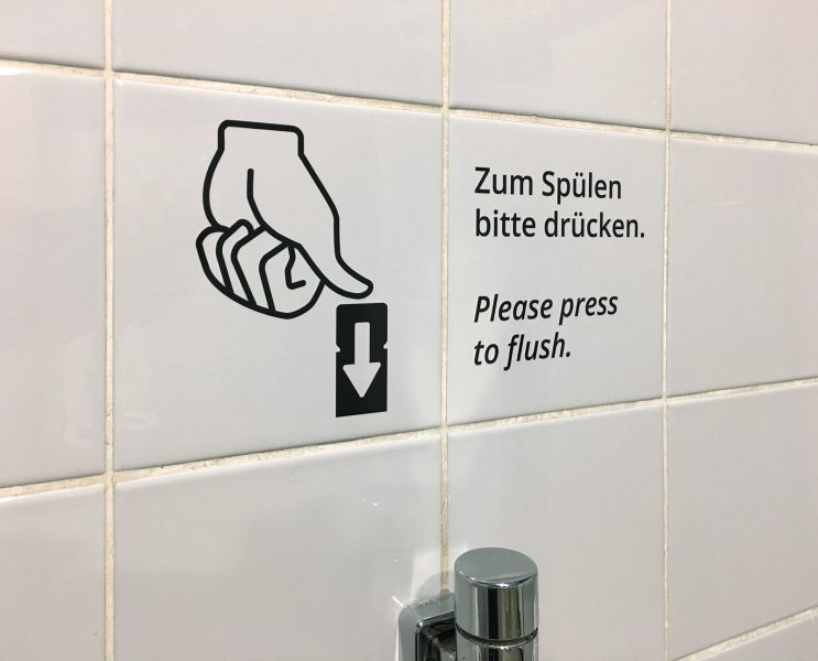 Hand Illustration und Text an Toilettenwand mit einem Hinweis