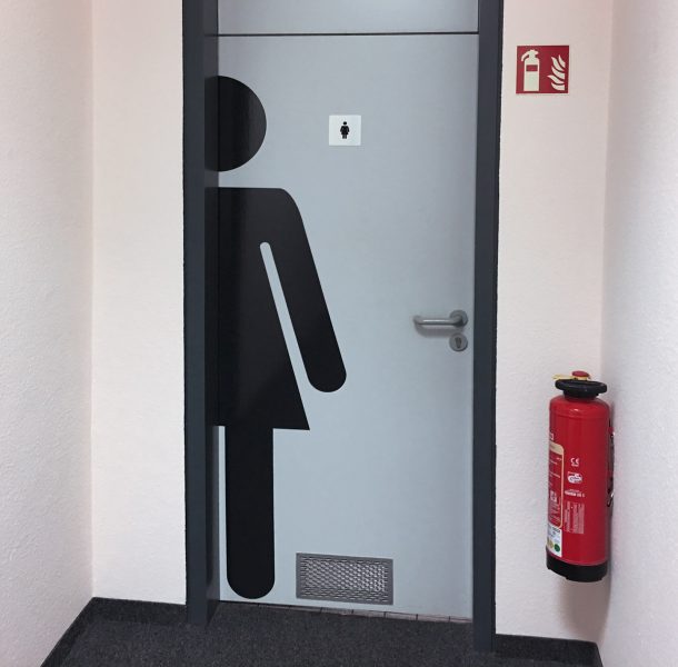 Lebensgroßes weibliches Toilettenmännchen angeschnitten und auf Toilettentüre geklebt