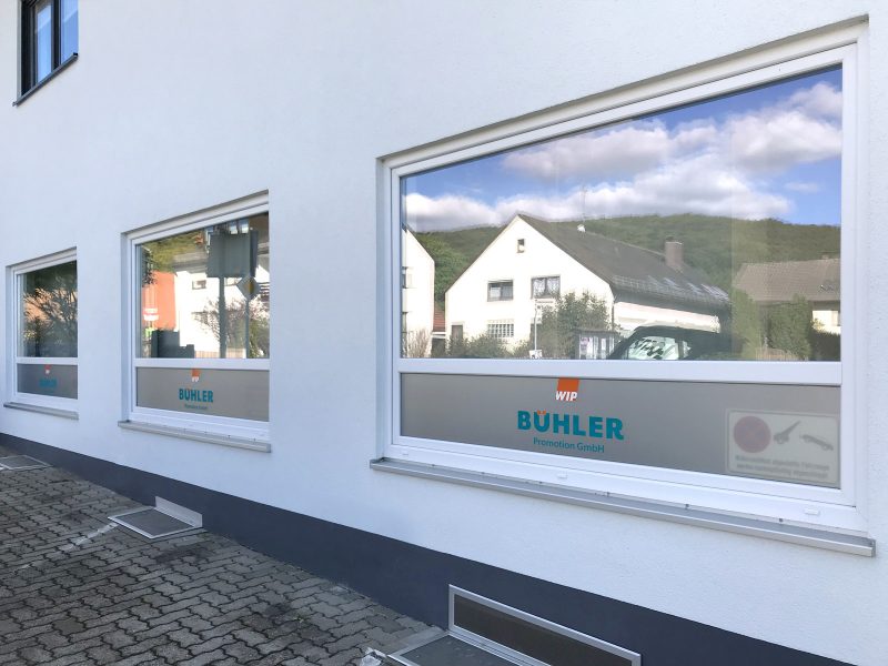 Fensterbeklebung - Drei große Fenster, die mit Sichtschutzfolie und Logo auf der untersten Fensterscheibe für Bühler Promotion foliert sind