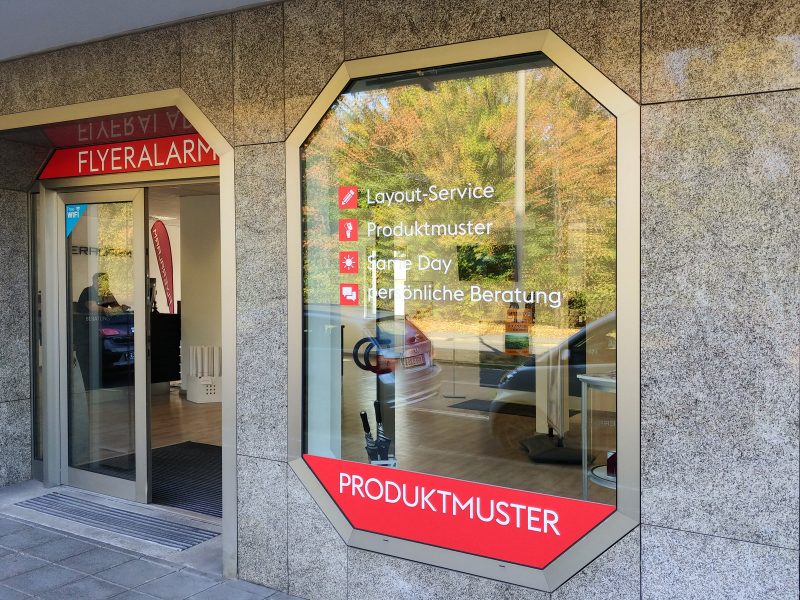 Schaufensterfolierung - Eingangsbereich der Werbeagentur Flyeralarm mit Folienbeschriftung an Schaufenster und Oberlicht