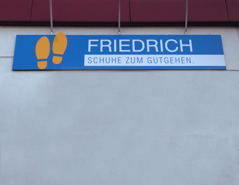 Beklebung - Nahaufnahme eines großes Fassadenschildes für den Schuhladen Friedrich