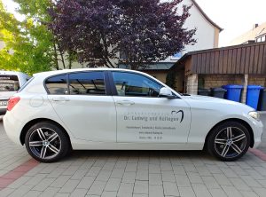 KFZ-Beklebung - Seitenansicht eines weißen BMWs mit neuer Folienbeschriftung für Zahnarzt Ludwig