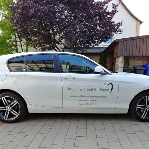 KFZ-Beklebung - Seitenansicht eines weißen BMWs mit neuer Folienbeschriftung für Zahnarzt Ludwig