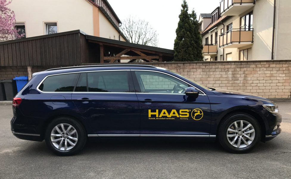 Fahrzeugbeklebung - Seitenansicht eines dunkelblauen Passats mit neuer Fahrzeugbeschriftung für die Firma Haas