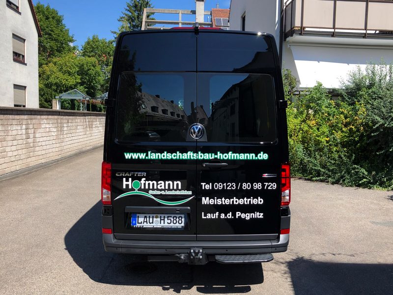 Heckansicht eines schwarzen Lieferwagens mit neuer Folienbeschriftung von Garten- und Landschaftsbau Hofmann