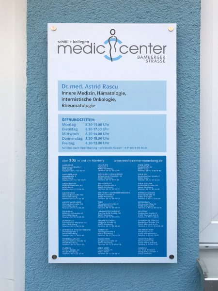 Alu-Dibond-Schild mit Edelstahlabstandshaltern an einer blauen Hauswand für Medic Center