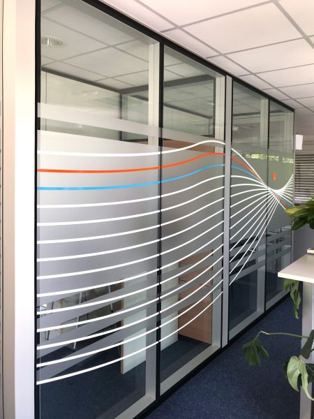 Auffallender Sichtschutz - Sichtschutzfolierung aus Milchglasfolie mit darauf geklebten farbigem Muster auf einer Glasfront in Büroräumlichkeiten der Firma isyst