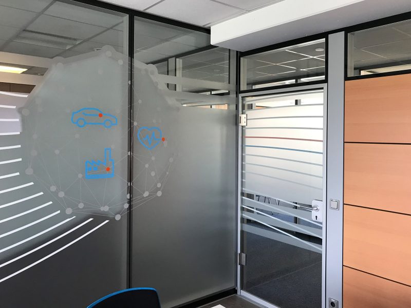 Sichtschutzfolierung aus Milchglasfolie mit darauf geklebten farbigem Muster auf einer Glasfront in Büroräumlichkeiten der Firma isyst