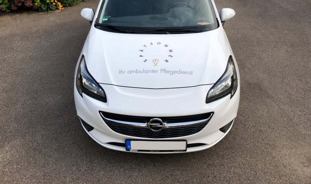 Fahrzeugfolierung - Frontansicht eines weißen Opel mit Beklebung für Spätsommer Pflegedienst