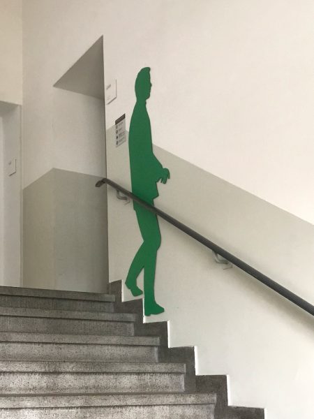 Grüne männliche Schattenfigur in einem Treppenhaus an der Wand