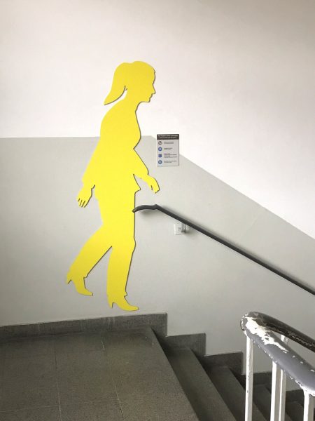 Schattenfiguren - Gelbe weibliche Schattenfigur in einem Treppenhaus an der Wand