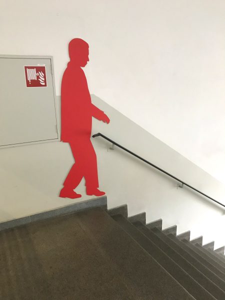 Rote männliche Schattenfigur in einem Treppenhaus an der Wand