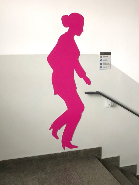 Schattenfiguren - Pinke weibliche Schattenfigur in einem Treppenhaus an der Wand