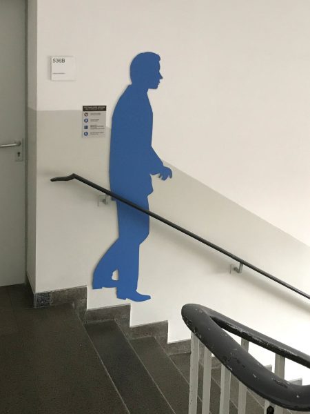 Blaue männliche Schattenfigur in einem Treppenhaus an der Wand
