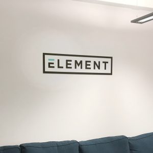 Beklebungsarbeiten - An einer weißen Wand hängt ein Alu-Dibond Schild mit dem Firmen Logo von Element