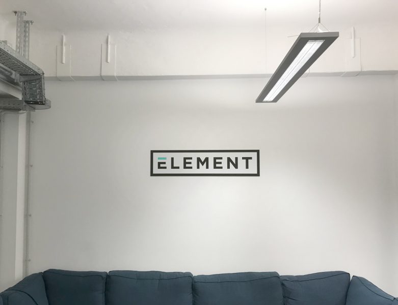 Beklebungsarbeiten - An einer weißen Wand hängt ein Alu-Dibond Schild mit dem Firmen Logo von Element
