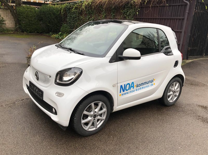 Fahrzeugbeklebung -Weißer Smart mit einem NOA kommunal Logo an der Seite