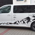 Fahrzeugbeklebung - Seitenansicht eines weißen Fahrzeuges mit Aufklebern im Alpendesign