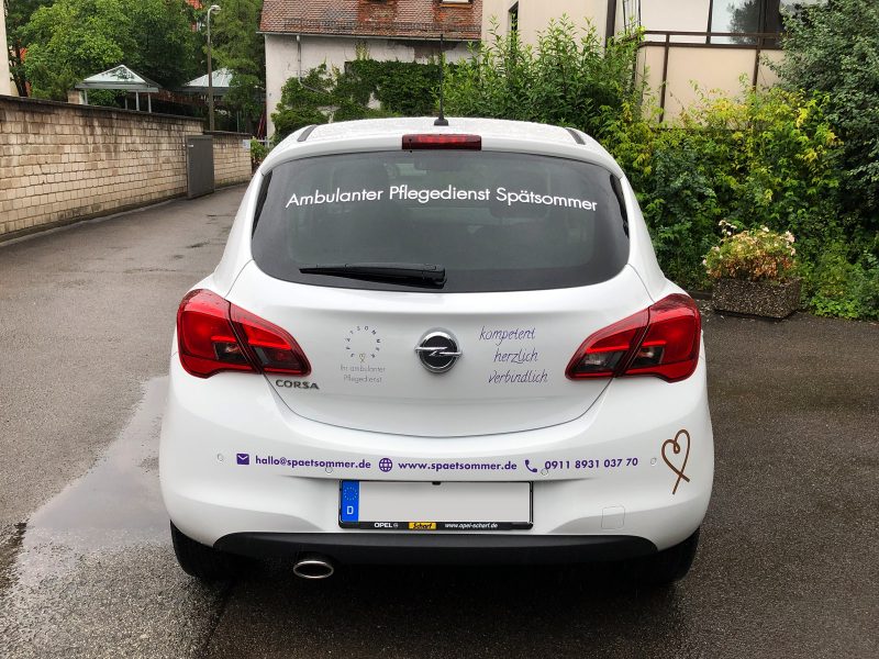 Heckansicht eines neu folierten weißen Opel Corsa für den Spätsommer Pflegedienst
