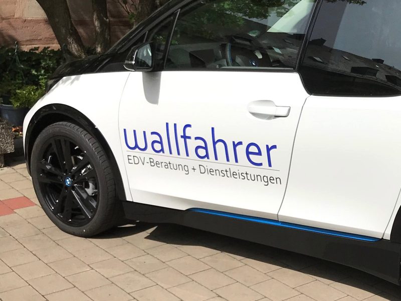 Schräge Seitenansicht von hinten links: Neuer BMW i3 mit Logofolierung an der Fahrertüre für die Wallfahrer GmbH