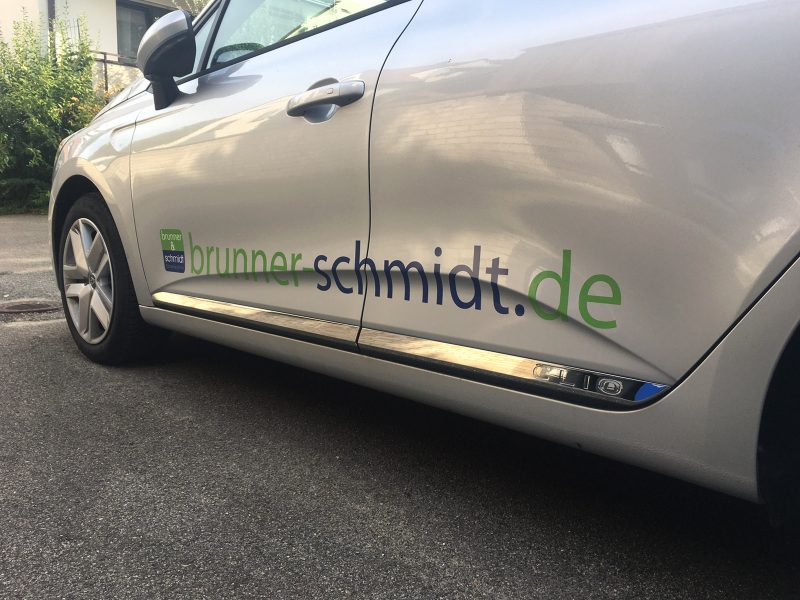 Schräge Seitenansicht eines silbernen Renault Clio mit neuer Folienbeschriftung für Brunner und Schmidt