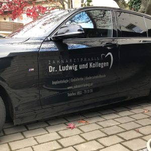 Seitenansicht eines schwarzen BMW 1er mit dezenter Folienbeschriftung für die Zahnarztpraxis Dr. Ludwig aus Fürth