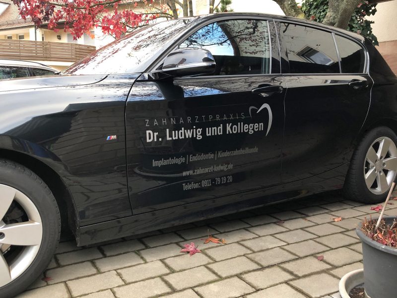Seitenansicht eines schwarzen BMW 1er mit dezenter Folienbeschriftung für die Zahnarztpraxis Dr. Ludwig aus Fürth
