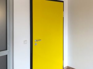 Tür-Vollfolierung - Schwarzer Türrahmen und gelbes Türblatt im Auftrag der Diakonie