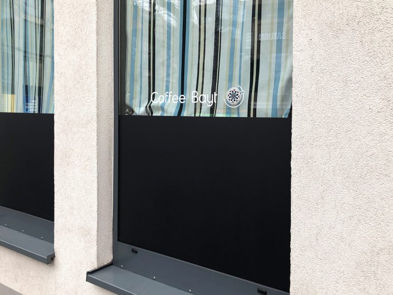 Café Folierung - Detailaufnahme eines folierten Fensters mit schwarzer Folie und Logo