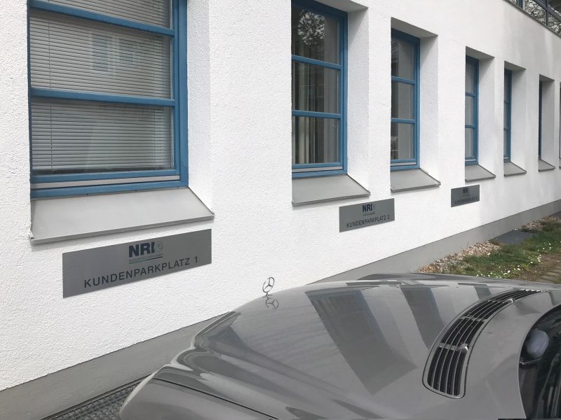 Firmenbeschilderung - Edelstahl gebürstete NRI Parkplatzschilder an Fassade