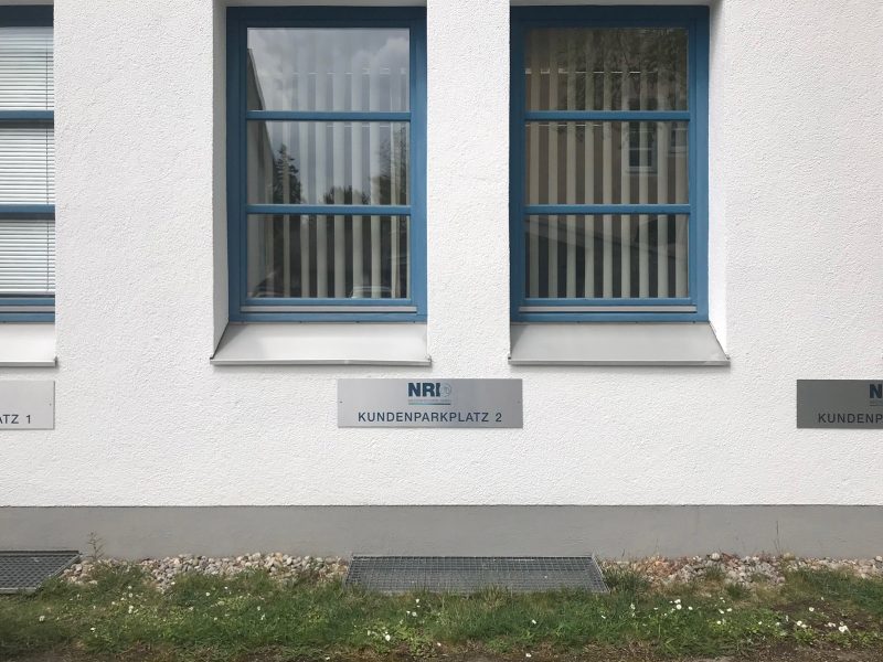 Firmenbeschilderung - Edelstahl gebürstetes NRI Parkplatzschild an Fassade