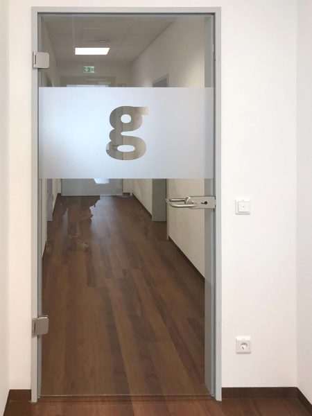 Durchlaufschutz an einer Glastür zum Gang bei Geneon | Folie mit Logo